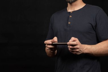 Ekranın sağ tarafında mavi tişörtlü bir adama yaklaş. İki eliyle akıllı telefon tut.