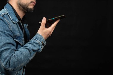 Kot ceket giyen bir adama yaklaş. Çağrı konseptinde akıllı telefonu ağzına yakın tut.