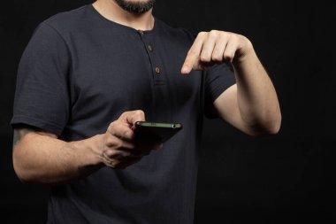 Bluet tişört giyen bir adama yaklaş ve işaret parmağıyla akıllı telefon ekranının üzerindeki boşluğu göster.