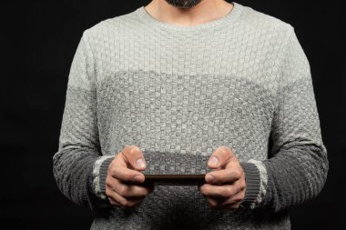 Önünde akıllı telefon ekranına başparmaklarıyla yazı yazan beyaz kazaklı bir adama yaklaş.