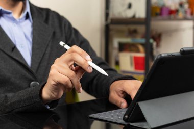 Ekranın sol tarafında, sağ eli tablet ekranını gösteren dijital bir kalem tutan modern bir iş adamına yakın durun.