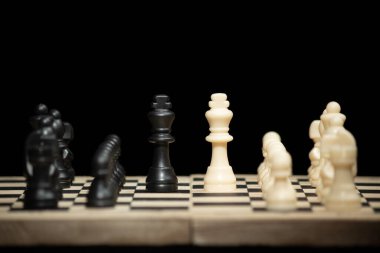 Bir satranç tahtası ve siyah arkaplan üzerinde karşı karşıya bir kral satranç taşı yakın