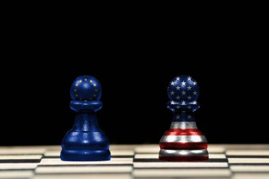 Bir satranç tahtası ve jeopolitik konseptte siyah arkaplan üzerinde Avrupa Birliği ve Amerika Birleşik Devletleri bayrakları olan iki piyona yakın satranç taşı
