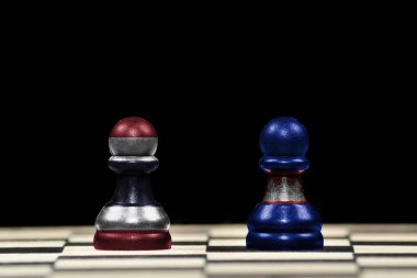 Satranç tahtası üzerinde Tayland ve Kamboçya bayrakları ve jeopolitik konseptte siyah arka plan olan iki piyona yakın satranç taşı