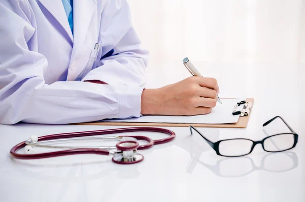 Doctor writing on table — Stock Photo, Image
