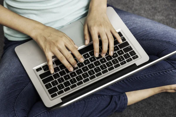 Jonge vrouw zitten terwijl het gebruiken van laptop — Stockfoto