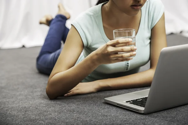 Junge Frau legt während sie Laptop benutzt — Stockfoto