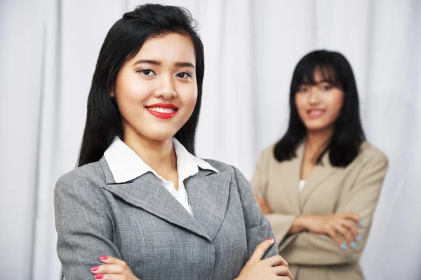 Businesswomen wearing suits standing and folding arms — Stock Photo, Image