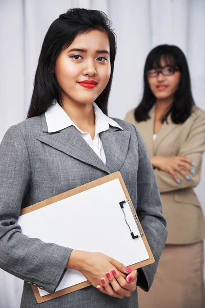 Businesswomen wearing suits standing and folding arms — Stock Photo, Image