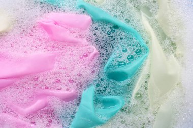 Renkli giysiler toz deterjana batırılmış su çözeltisi. Çamaşır konsepti