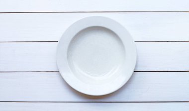 Beyaz ahşap arka planda boş seramik tabak. Boşluğu kopyala