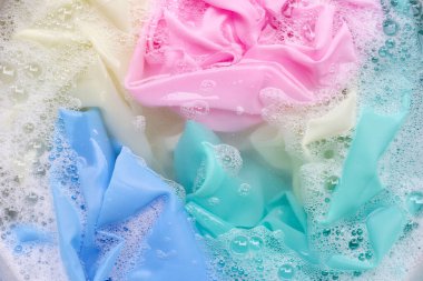 Renkli giysiler toz deterjana batırılmış su çözeltisi. Çamaşır konsepti