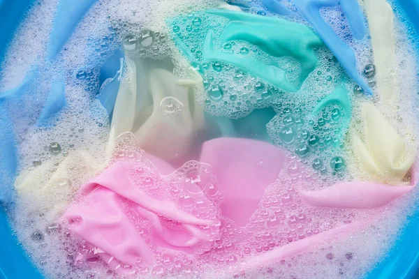 Renkli giysiler toz deterjana batırılmış su çözeltisi. Çamaşır konsepti