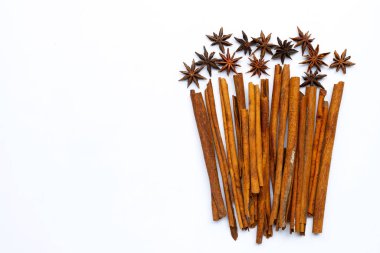 Beyaz arkaplanda yıldız anisi ve tarçın çubukları.