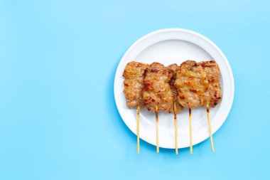 Mavi arka planda beyaz tabakta ızgara domuz eti. Boşluğu kopyala