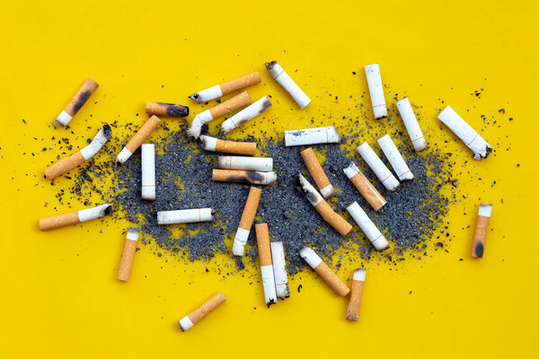 Cigarettes buds with ashtray on  yellow background. 