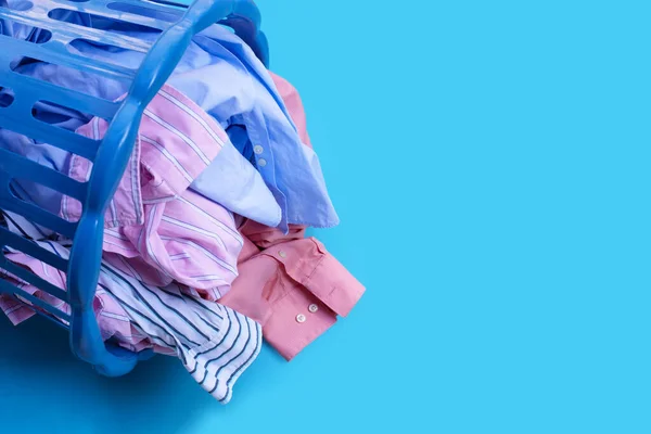 Clothes with a laundry basket on blue background. Copy space
