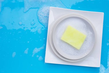 Bulaşık yıkama konsepti ıslak mavi arka planda. Üst görünüm