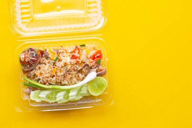 Sarı arka planda plastik kutuda kızarmış pirinç..