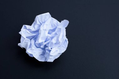 Koyu arka planda buruşmuş beyaz kağıt top. Boşluğu kopyala