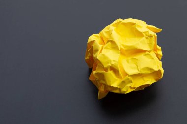 Koyu arka planda buruşmuş sarı kağıt top. Boşluğu kopyala