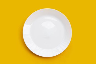 Sarı arkaplanda boş beyaz tabak. 