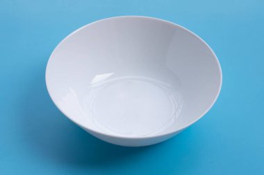 Mavi arkaplanda boş beyaz kase. 