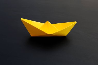 Koyu arka planda sarı kağıt tekne. Boşluğu kopyala