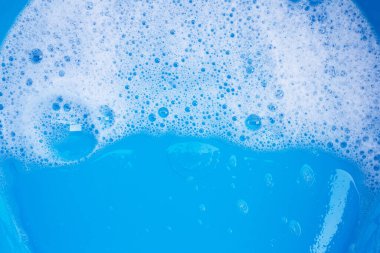 Deterjan köpüğü mavi arka planda. Üst görünüm