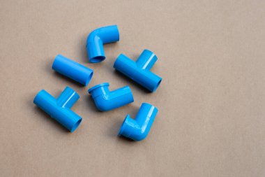 Kahverengi kağıt arka planda mavi pvc boru bağlantısı.