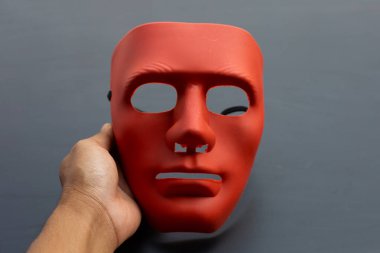 Karanlık arka planda el ele tutuşan yüz maskesi.