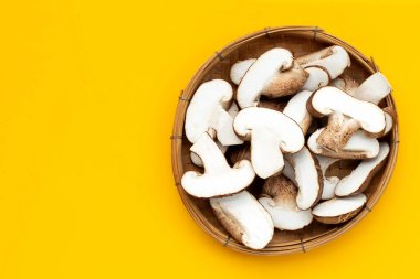 Taze Shiitake mantarları sarı arka planda bambu sepetinde dilimler..
