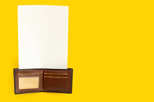 黄色の背景に白い紙で茶色の財布 スペースのコピー — ストック写真
