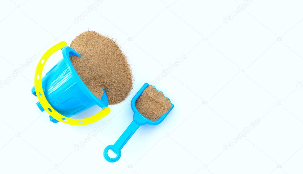 Plastic toys, shovel and bucket with sand on white background. Summer background concept