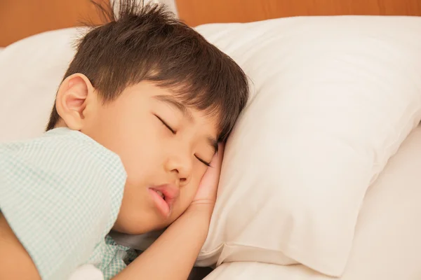 Aziatische jongen in slaap op het bed. — Stockfoto