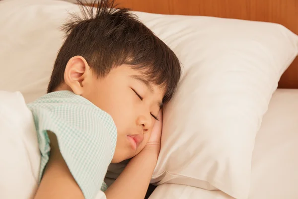 Aziatische jongen in slaap op het bed. — Stockfoto