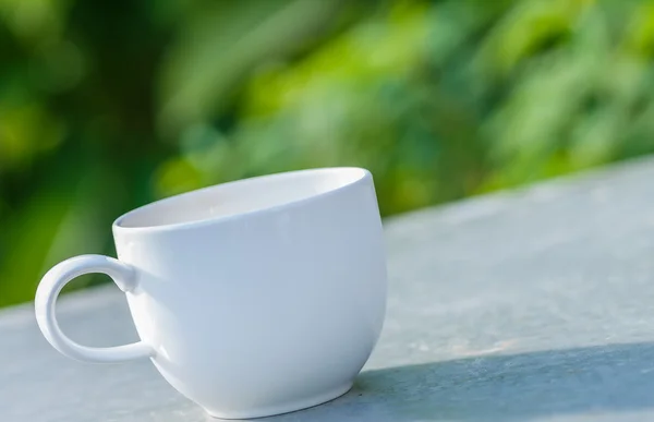 Cup of coffee on  table in green garden — Stock Photo, Image