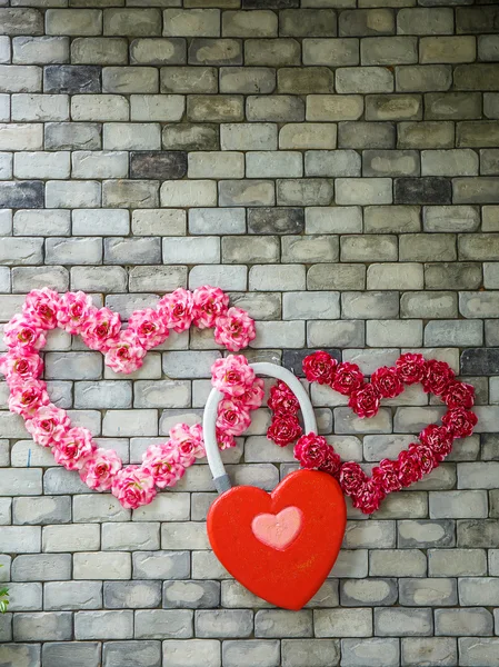 Heart-shaped flowers on a brick wall — Stock Photo, Image