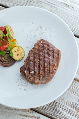 bir tabak biftek ve ızgara sebzeler