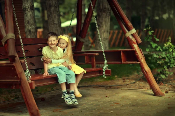 Jongen met het meisje op een schommel — Stockfoto