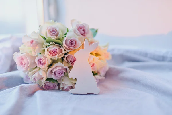 Bouquet van rozen en een houten konijn — Stockfoto