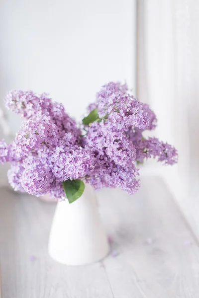 Ein Strauß Flieder in einer weißen Vase — Stockfoto