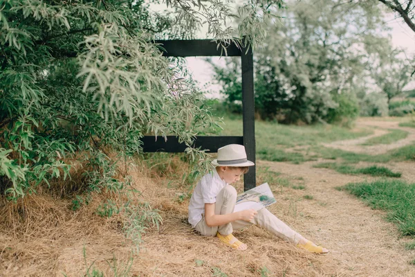 Menino lendo um livro sobre a natureza — Fotografia de Stock