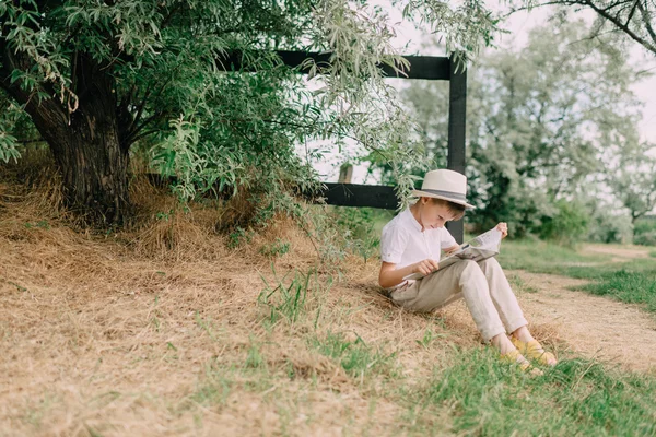 Chico leyendo un libro sobre la naturaleza — Foto de Stock