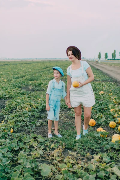 Mãe e filho em um campo com melões — Fotografia de Stock