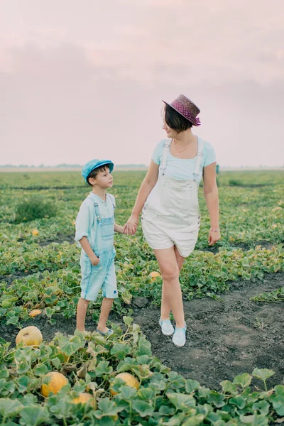Mãe e filho em um campo com melões — Fotografia de Stock