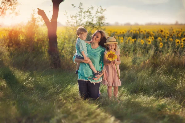 Mutter mit Kindern in Sonnenblumen — Stockfoto