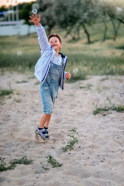 Un niño pequeño en jeans en la arena —  Fotos de Stock