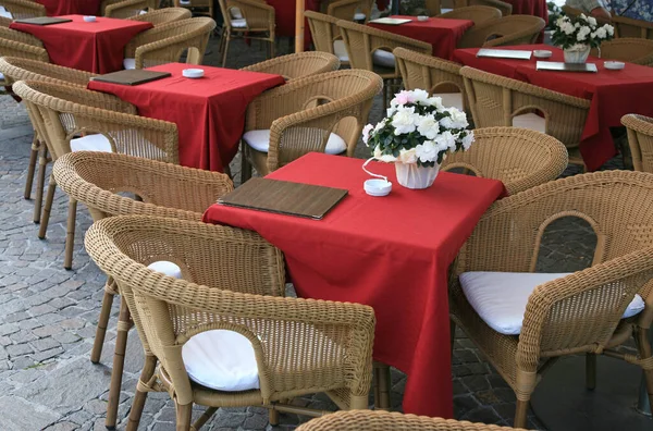 Dışarıdaki bir restoranda masa örtüsü ve sandalyeli boş masalar.
