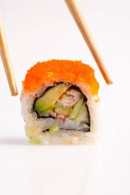 Sushi 'nin Makro Fotoğrafı Japon yemeklerini yemek çubuklarıyla beyaz arka planda izole ediyor. Ton balığı, sebze ve havyar ile Kaliforniya suşisi.